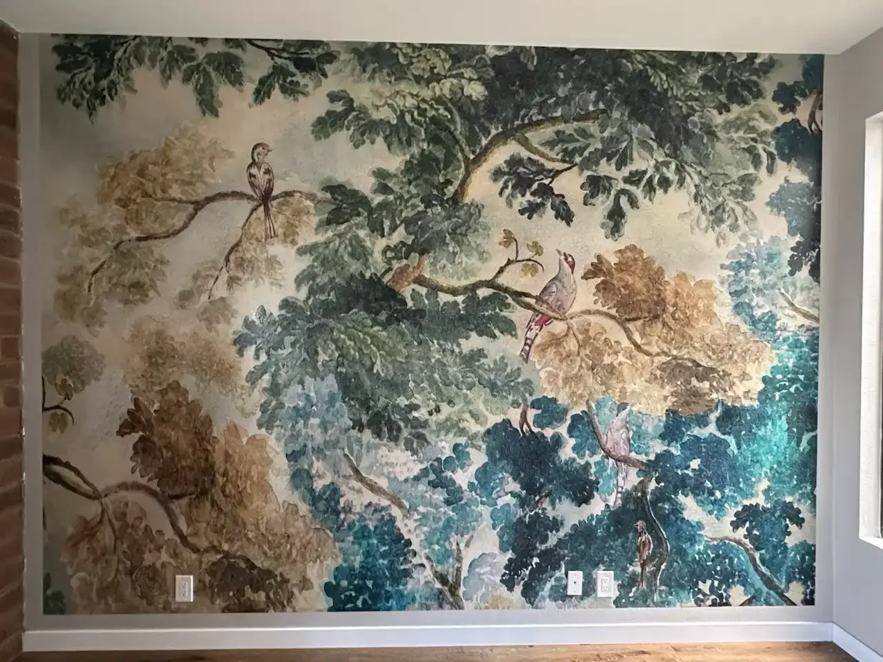 A large-scale botanical wallcovering with birds and layered foliage
