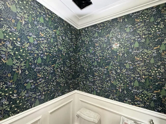 Dark floral wallpaper meeting a white paneled wall at a corner