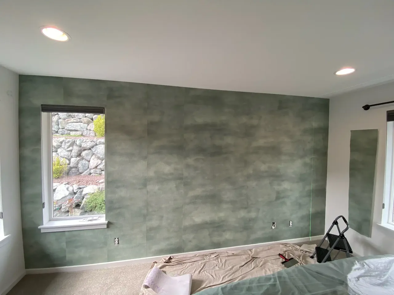 Muted green-gray wallcovering in a bright room with a window
